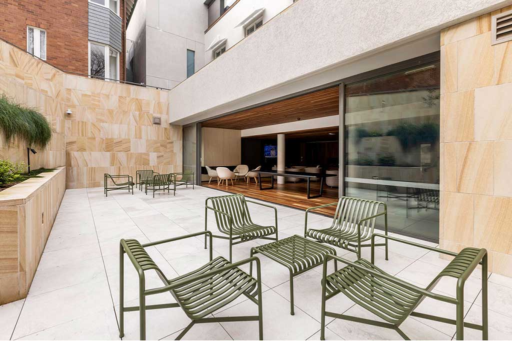 Outdoor space on level 1, with 2 sets of green outdoor furniture and a view back into the Centre in the breakout and coffee space.