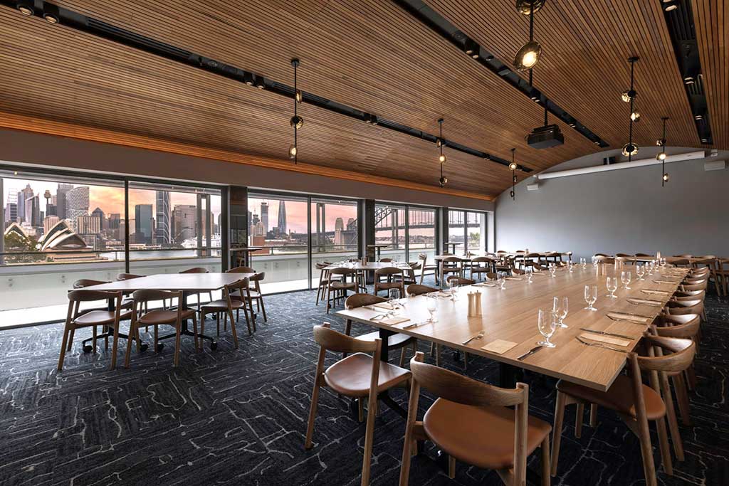 Level 4 dining room with main table setup with cutlery, a smaller table to the left and extensive views of Sydney Harbour, Sydney Harbour Bridge and the Opera House.